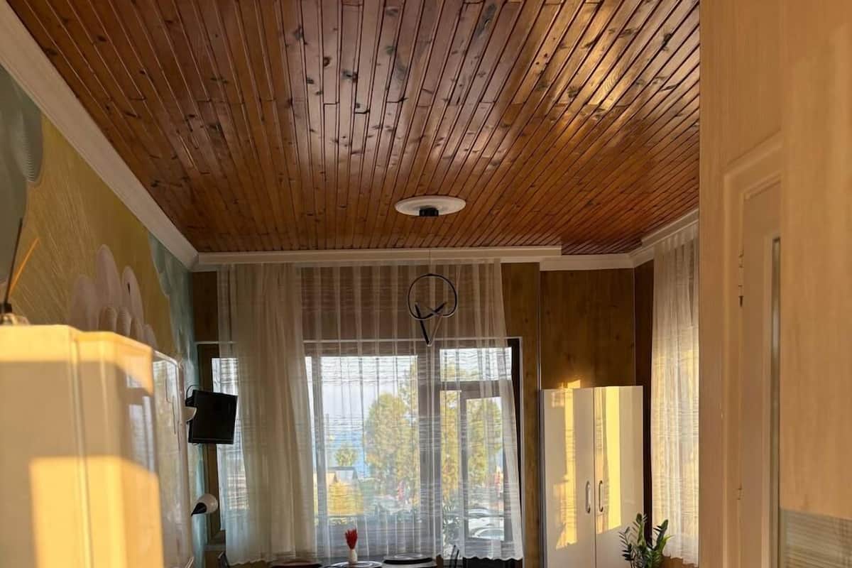Un espace de vie compact doté d’un plafond en bois, d’un coin repas avec une table et des chaises, d’un canapé et d’un lit.