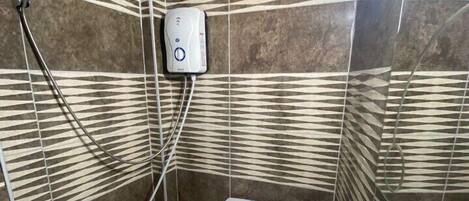 A bathroom with striped tile walls, a toilet, a sink, and a handheld showerhead.