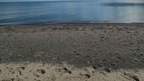 Een strand met een kiezelstrand, rustige zee en een gedeeltelijk bewolkte lucht.