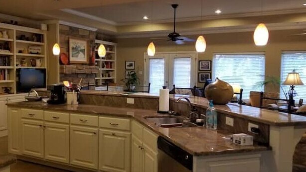 A spacious kitchen with a large island, built-in shelves, and a dining area with a table and chairs.