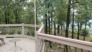 A wooden deck with a white railing, tables, and chairs.