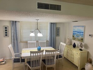 Enjoy meals in this dining area with a table for four, pendant light, and cream-colored cabinet.