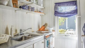 A kitchen with white cabinets, a sink, a stove, and a window with a blue curtain.