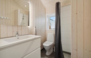 A bathroom with a wooden interior, a white sink, a toilet, and a shower curtain. - Nice home in Sydals with WiFi (Sydals)