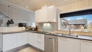 Cocina moderna con armarios blancos, electrodomésticos de acero inoxidable y una ventana con vistas al exterior.