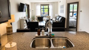 A modern kitchen with granite countertops, stainless steel sinks, and a dining area with a table and chairs.