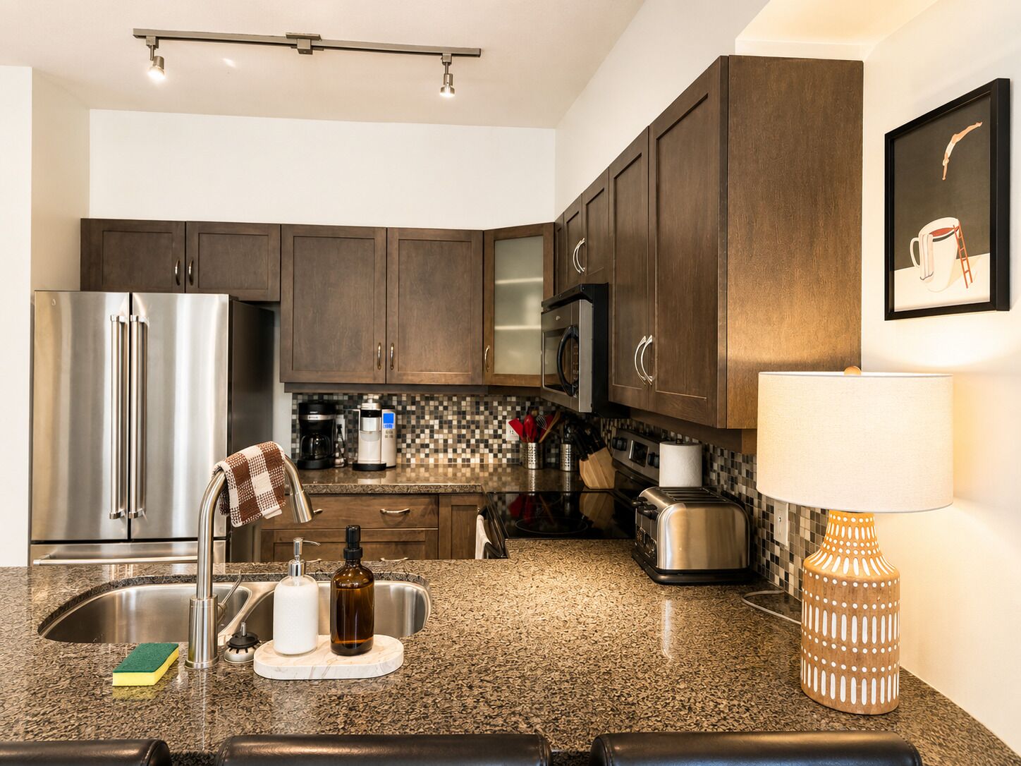 A modern kitchen with dark wood cabinets, stainless steel appliances, and a granite countertop.