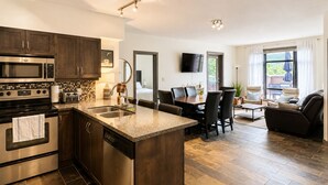 A modern kitchen with a central island, built-in appliances, and a dining area with a TV.