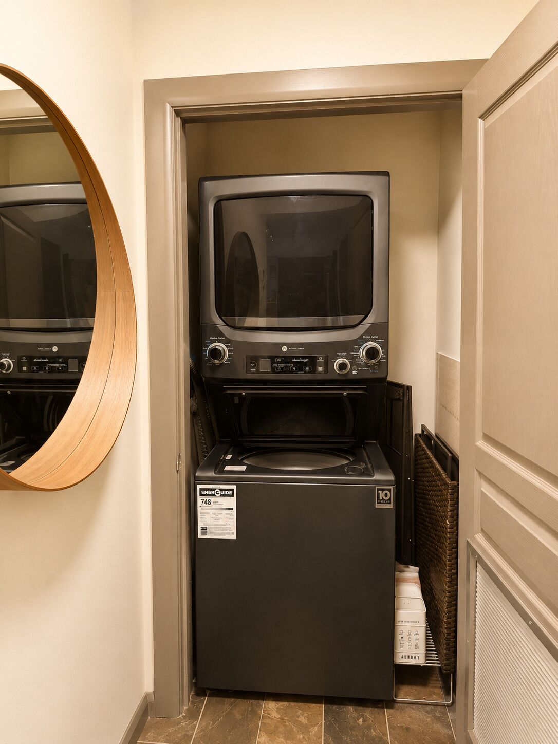 A compact laundry room with a washer and dryer, a mirror, and a small basket.