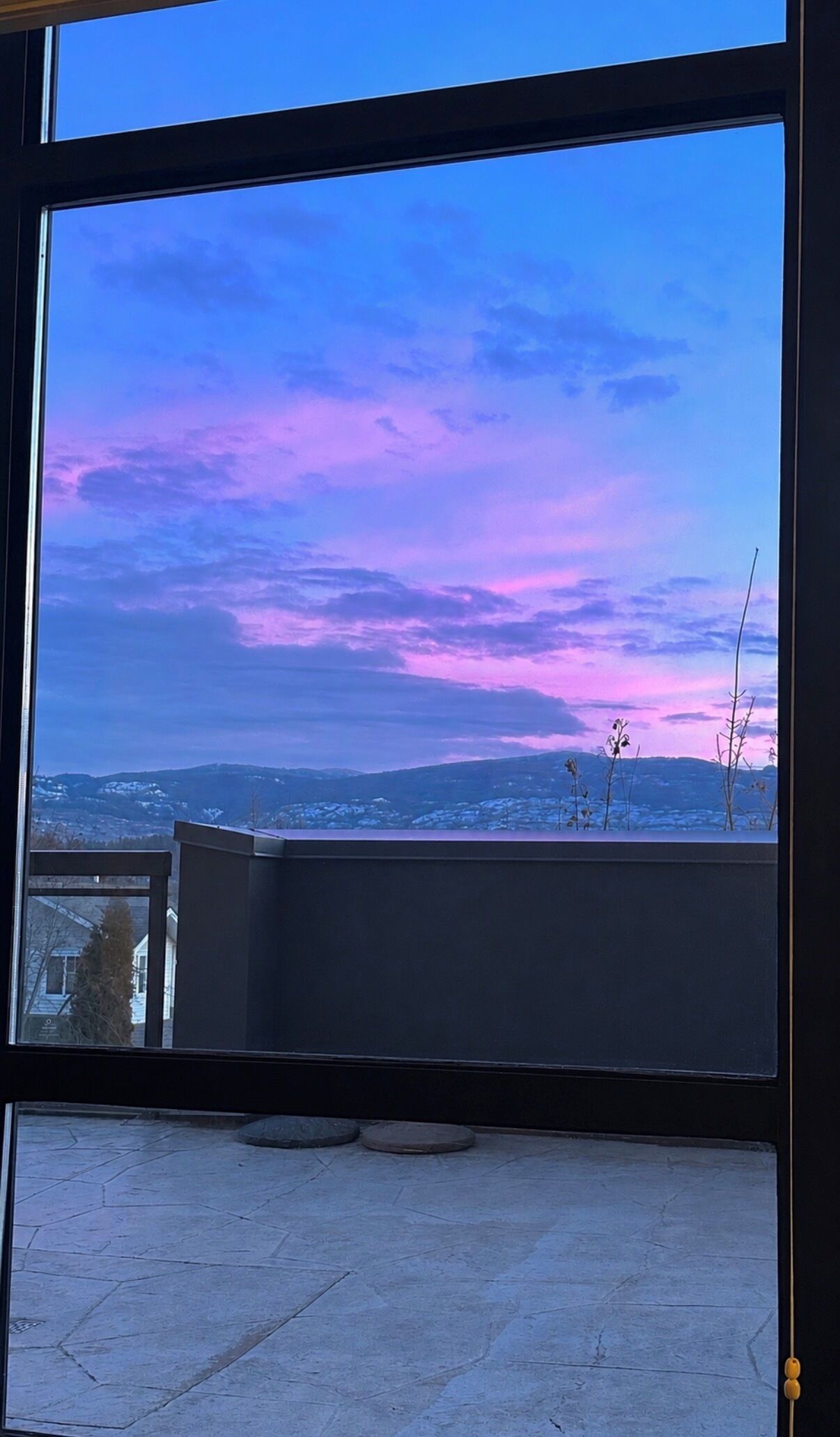 Blick durch ein Fenster auf einen klaren Himmel und eine entfernte Landschaft.