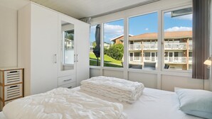 A bedroom with a bed, a wardrobe, and a window with a view of a building. - Pet friendly apartment in Allinge (Allinge)