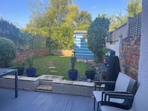 A patio area with a seating arrangement, potted plants, and a brick wall.