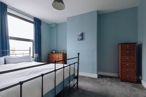 Une chambre à coucher avec un lit, une commode et un tableau accroché au mur.
