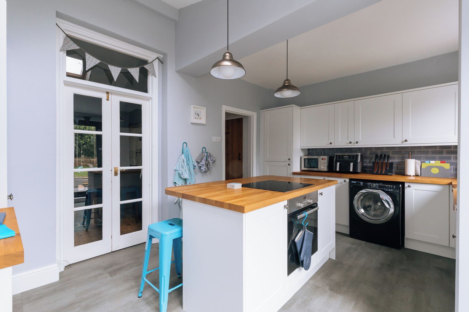 A modern kitchen with a built-in washing machine, a microwave, and a sink.