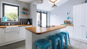 A modern kitchen with a wooden island, bar stools, a window, and a skylight. - Charming 3 BDR House Private Garden Bristol (Southville)