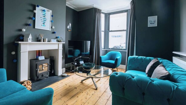 A living room with a fireplace, a TV, a sofa, and a chair. - Charming 3 BDR House Private Garden Bristol (Southville)