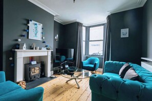 Ein Wohnzimmer mit Kamin, Fernseher, Sofa und Sessel.