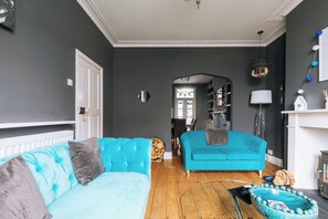 Un salon avec un canapé bleu, un plancher en bois et une porte blanche.