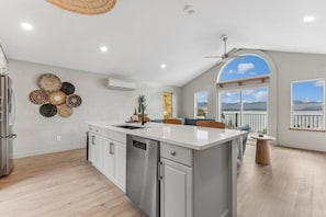 A spacious kitchen with a large island, white cabinetry, and a view of the outdoors through large windows. - Beautiful 6/5 home over looking Flathead Lake. (Somers)