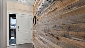 A hallway with a wooden wall and a white door. - Spacious Alpine Retreat - w/Hot Tub (Sun Peaks)