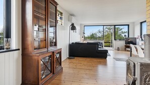 A spacious living room with a wooden cabinet, a black sofa, and a television.