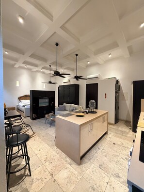 A modern kitchen with a central island, black cabinets, and a ceiling fan. - Loft en Casa Colonial del Centro Histórico. (Cartagena de Indias)