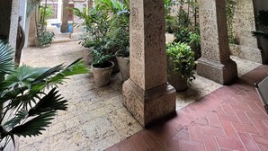 Un patio con arcos, plantas en macetas y vistas a un edificio con balcones.