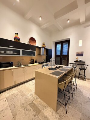 A modern kitchen with a central island, built-in appliances, and a dining area with bar stools.
