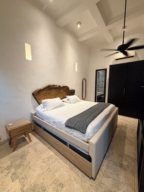 A bedroom with a bed, bedside table, and a ceiling fan.