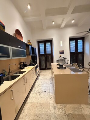 A modern kitchen with a central island, double doors, and a dining area. - Loft en Casa Colonial del Centro Histórico. (Cartagena de Indias)