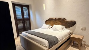 Une chambre à coucher comprenant un lit, une table de chevet, un ventilateur de plafond et une fenêtre avec des stores.