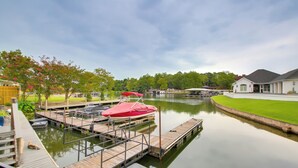A calm water body with docks, a red boat, and a white building in the background. - Hot Springs Retreat w/ Fireplace on Lake! (Hot Springs)