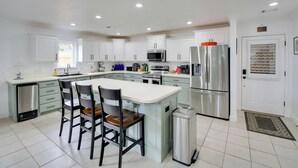 A modern kitchen with white cabinets, stainless steel appliances, and a central island with chairs. - Hot Springs Retreat w/ Fireplace on Lake! (Hot Springs)