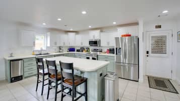 A modern kitchen with white cabinets, stainless steel appliances, and a central island with chairs.