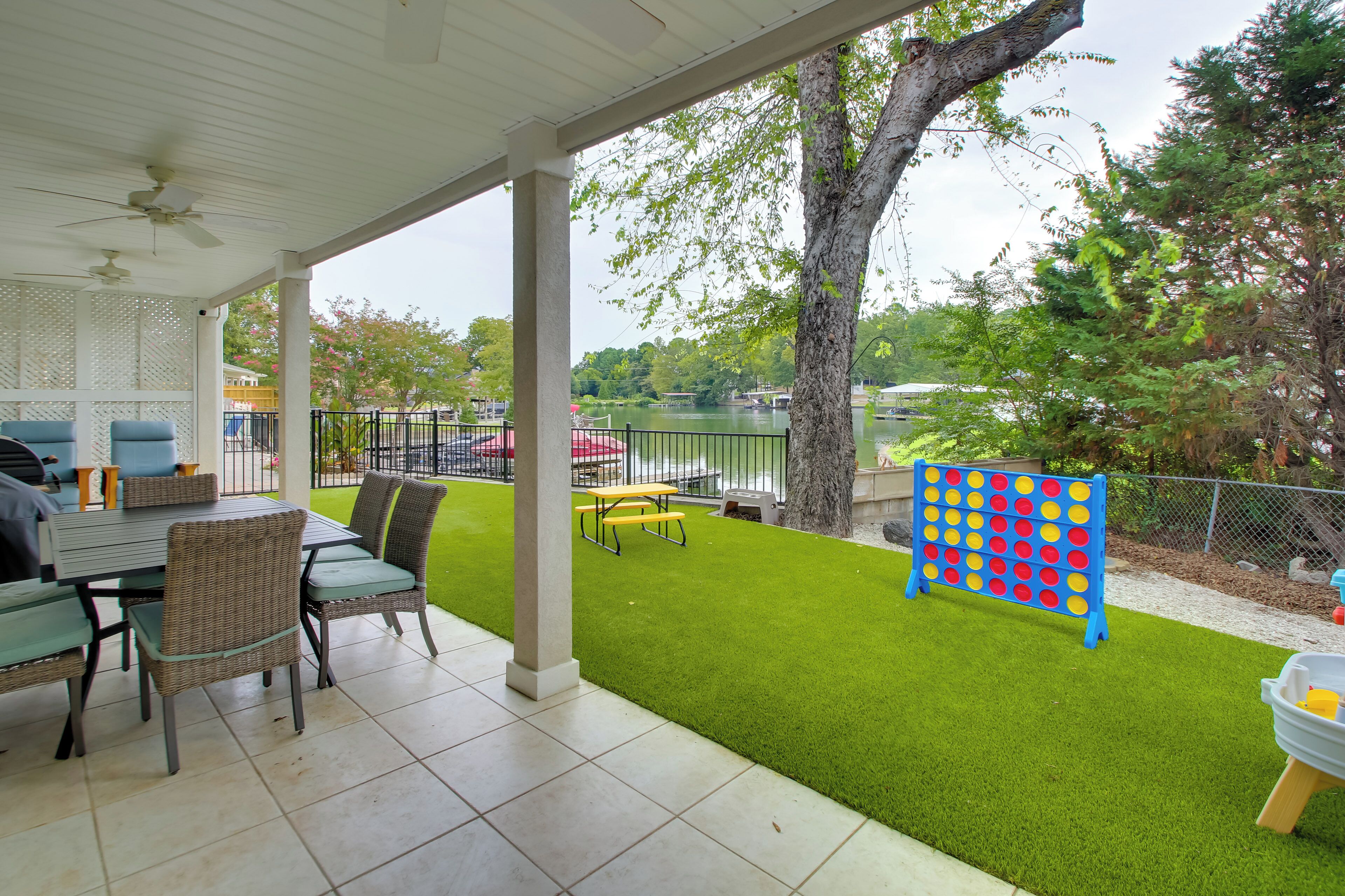 A covered patio with a table and chairs, a lawn, and a blue game board.