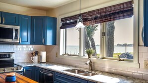 Una cocina con gabinetes azules, un lavamanos de acero inoxidable, un microondas y una estufa.