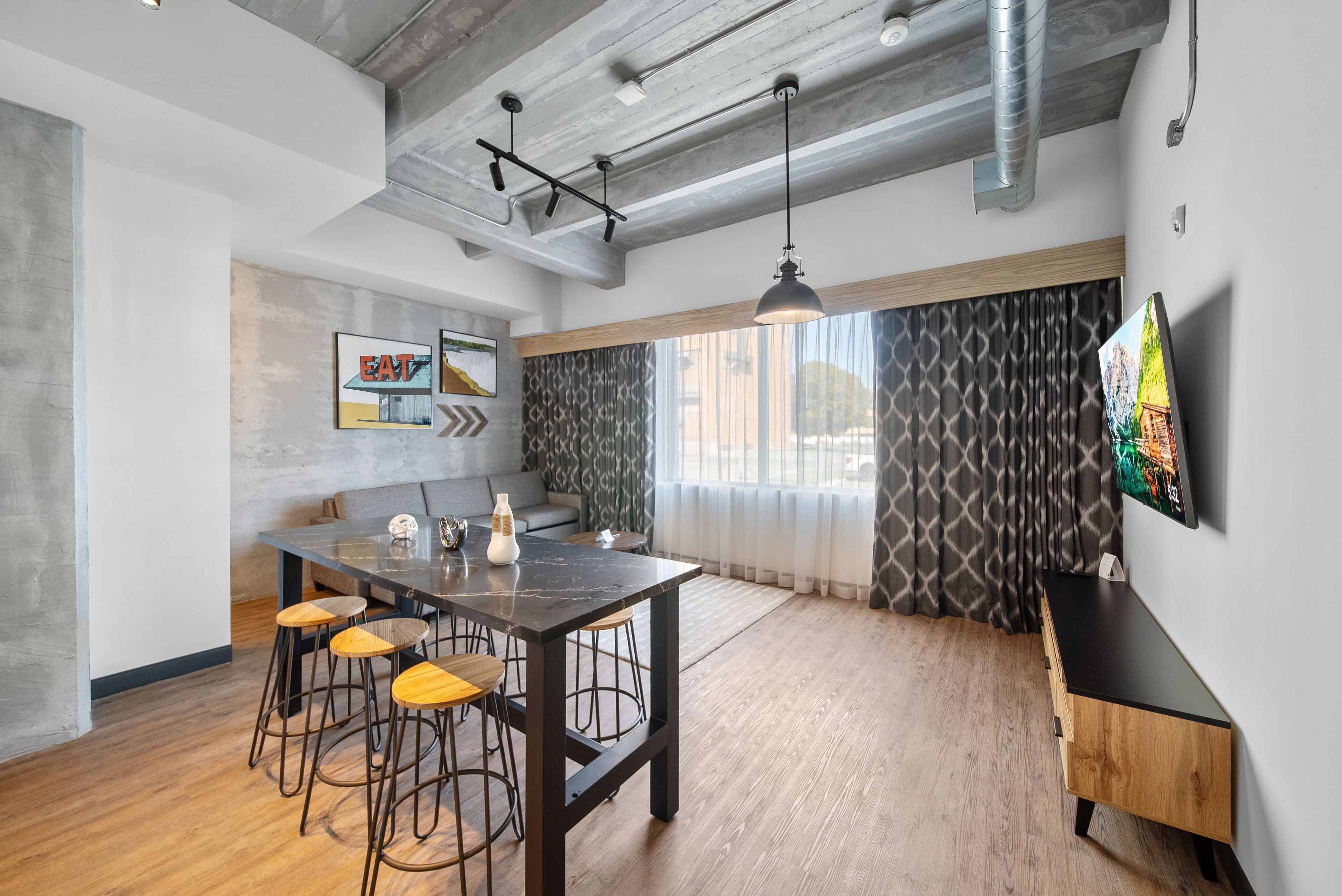 Una cocina moderna con una isla central, taburetes de bar y una mesa de comedor.