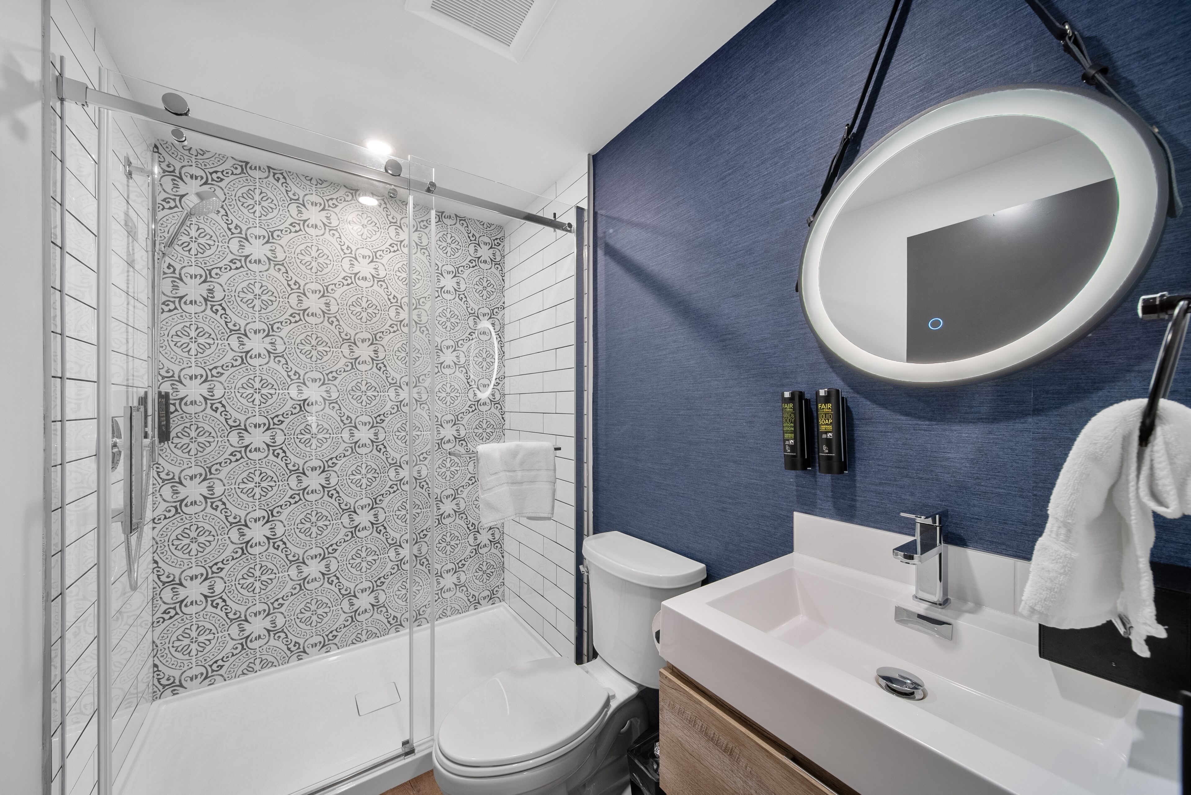 A modern bathroom with a shower, toilet, sink, and a large mirror.