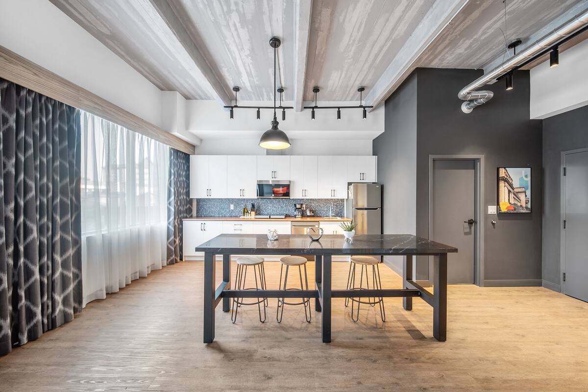A modern kitchen with a central island, pendant lighting, and a view of the cityscape.