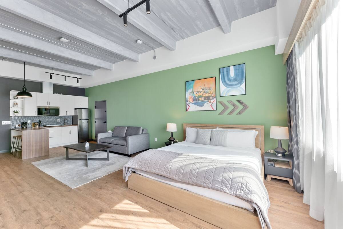 A modern bedroom with a bed, bedside tables, a desk, and a sofa.