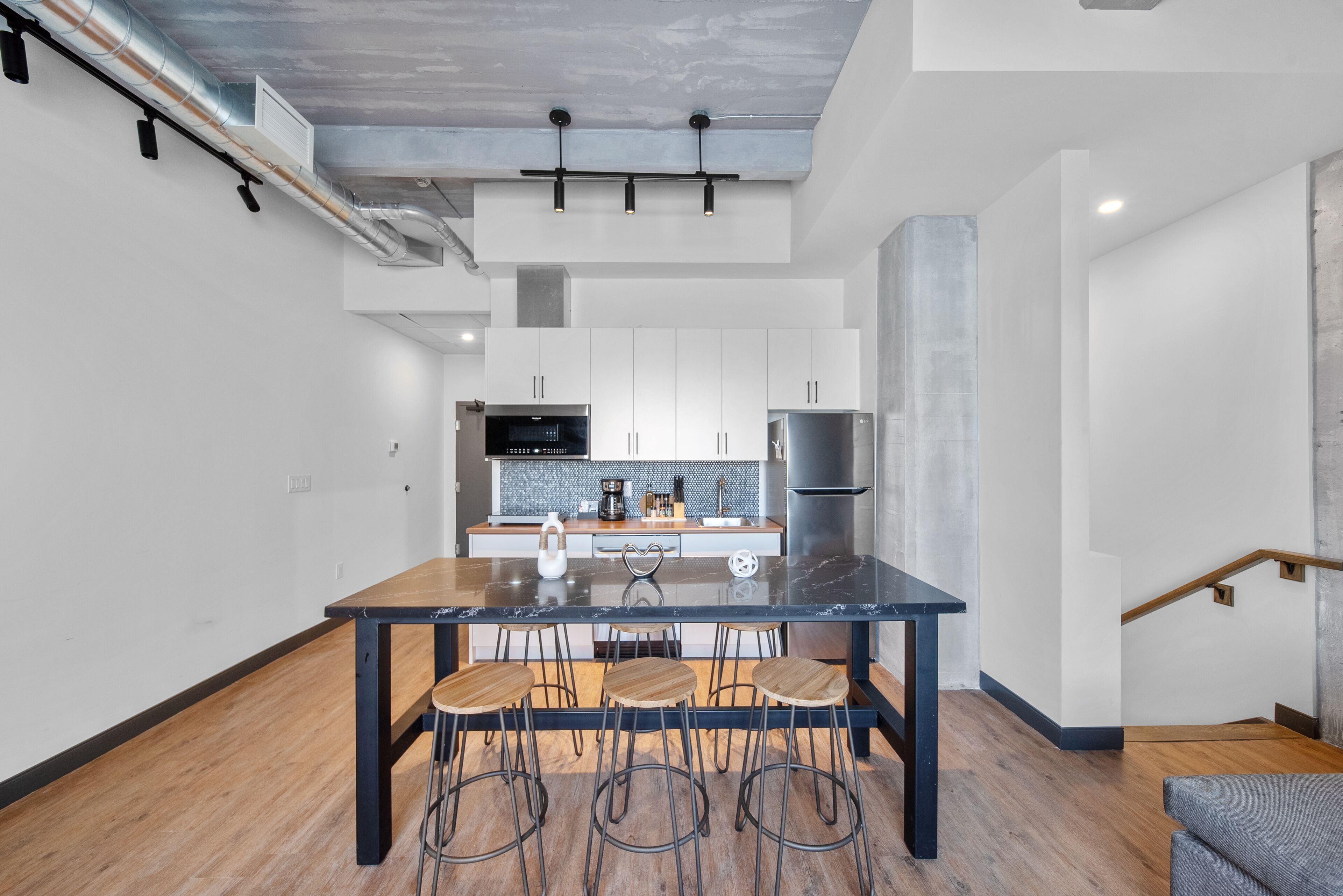 A modern kitchen with a central island, bar stools, and stainless steel appliances.