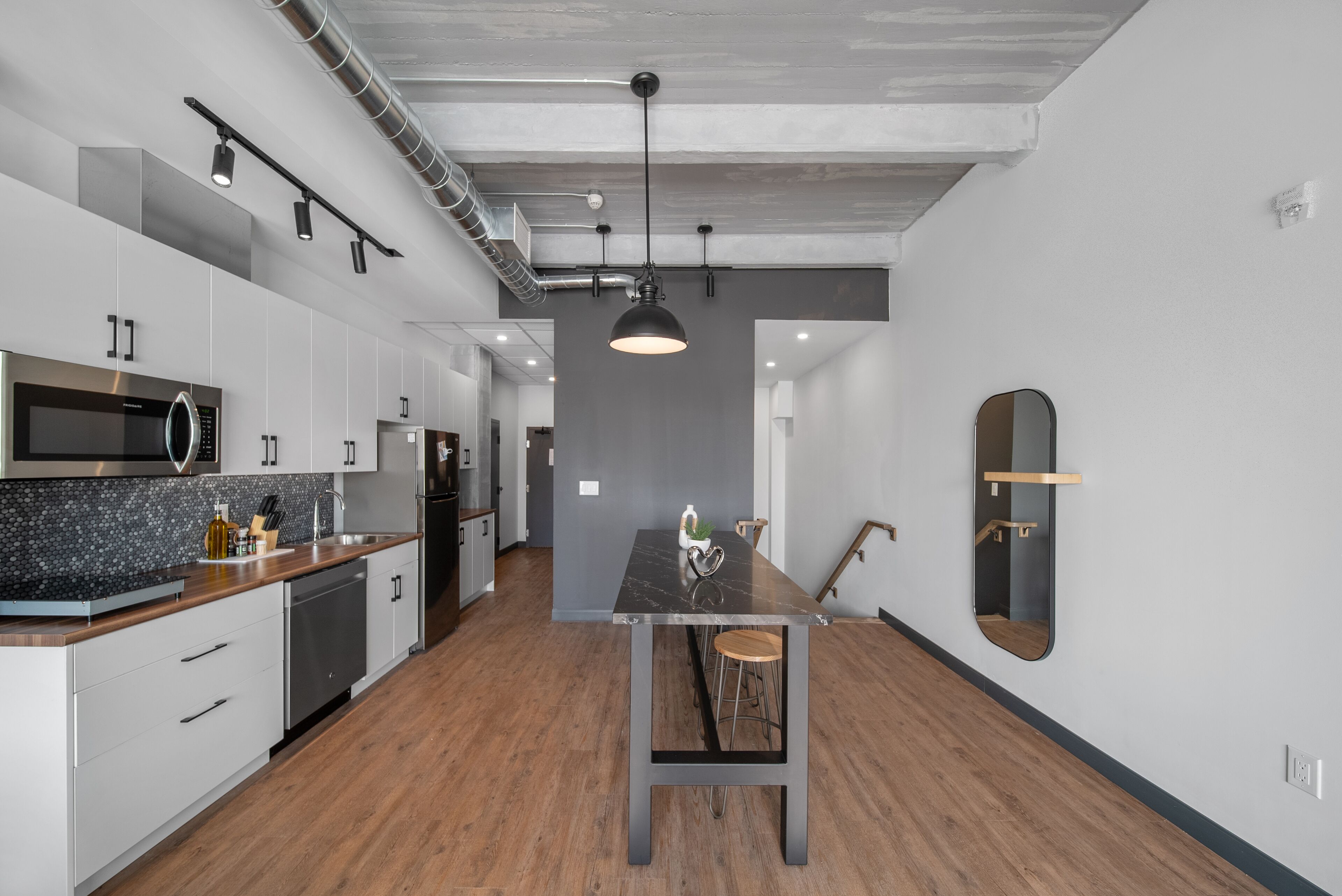 Una cocina moderna con electrodomésticos de acero inoxidable, encimera de mármol y una isla central con taburetes.
