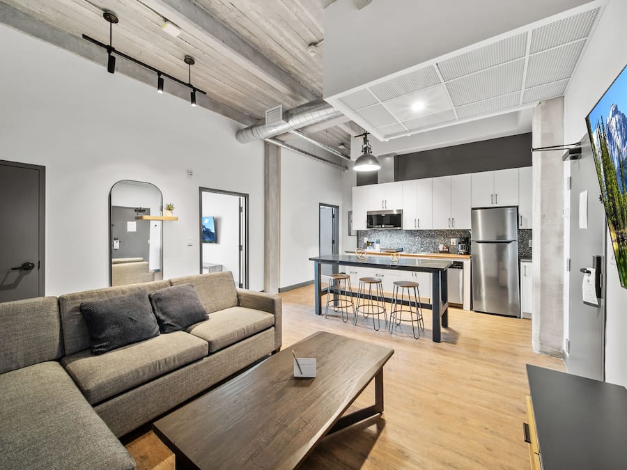 A modern kitchen with stainless steel appliances, a wooden dining table, and a bar area.