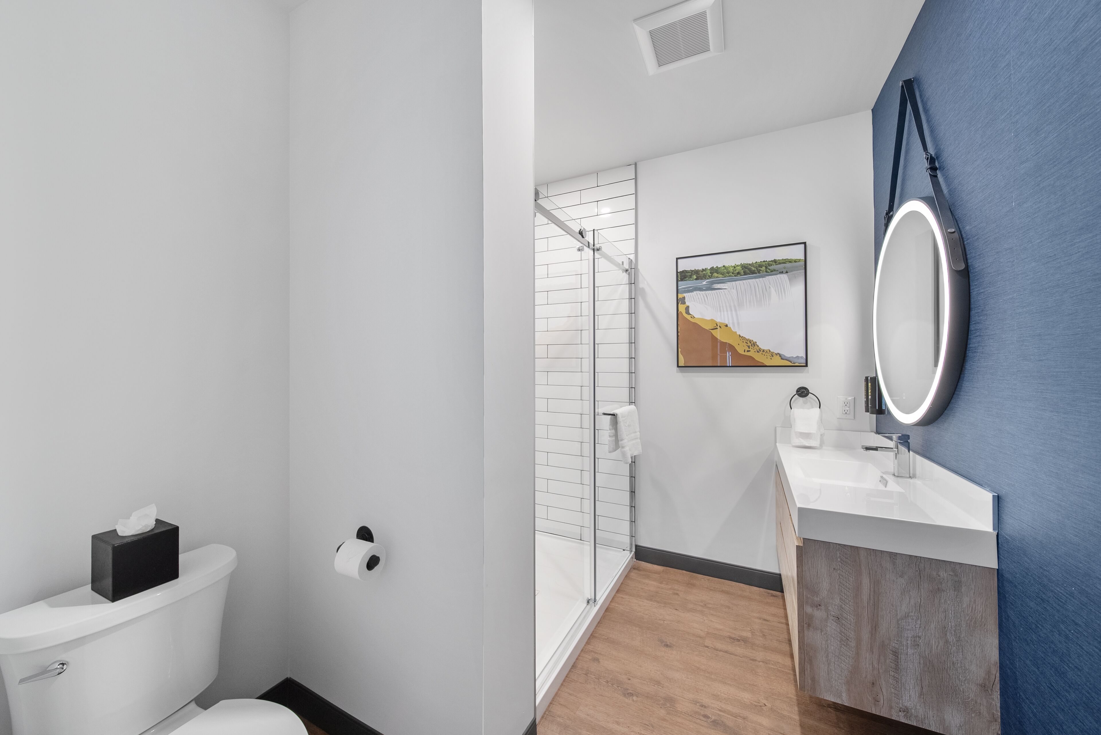 Un baño moderno con inodoro, ducha, lavabo y espejo.