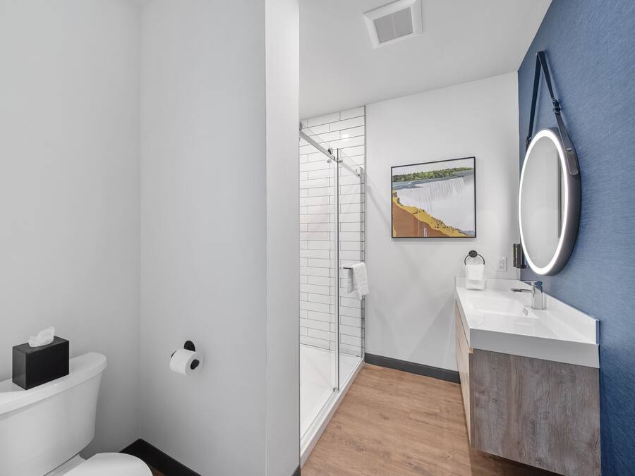 Un baño moderno con inodoro, ducha, lavabo y espejo.