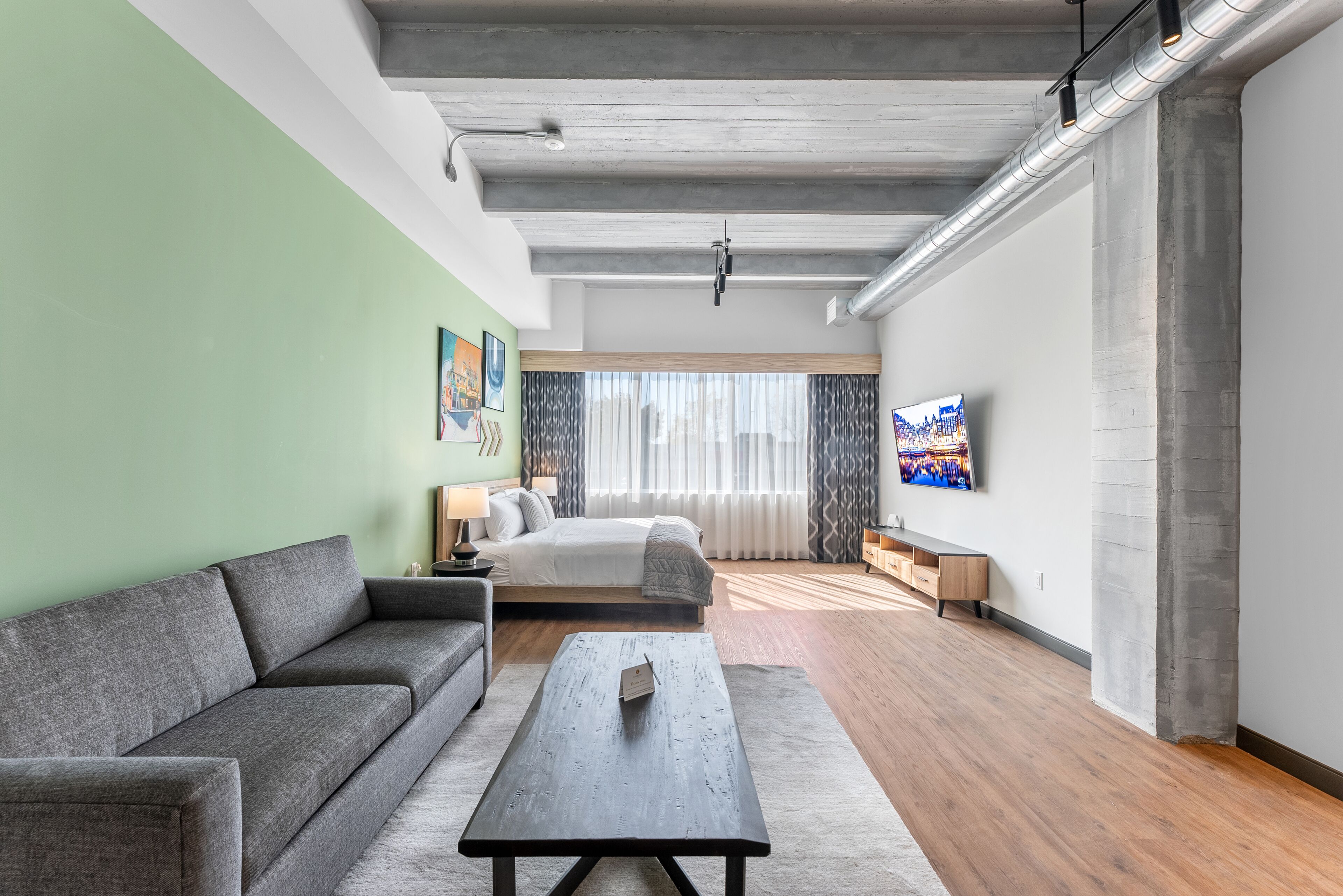 A modern living room with a sofa, a coffee table, a bed, and a TV.