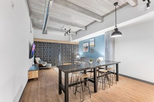 Una cocina moderna con encimera de mármol, taburetes de bar y una lámpara colgante.