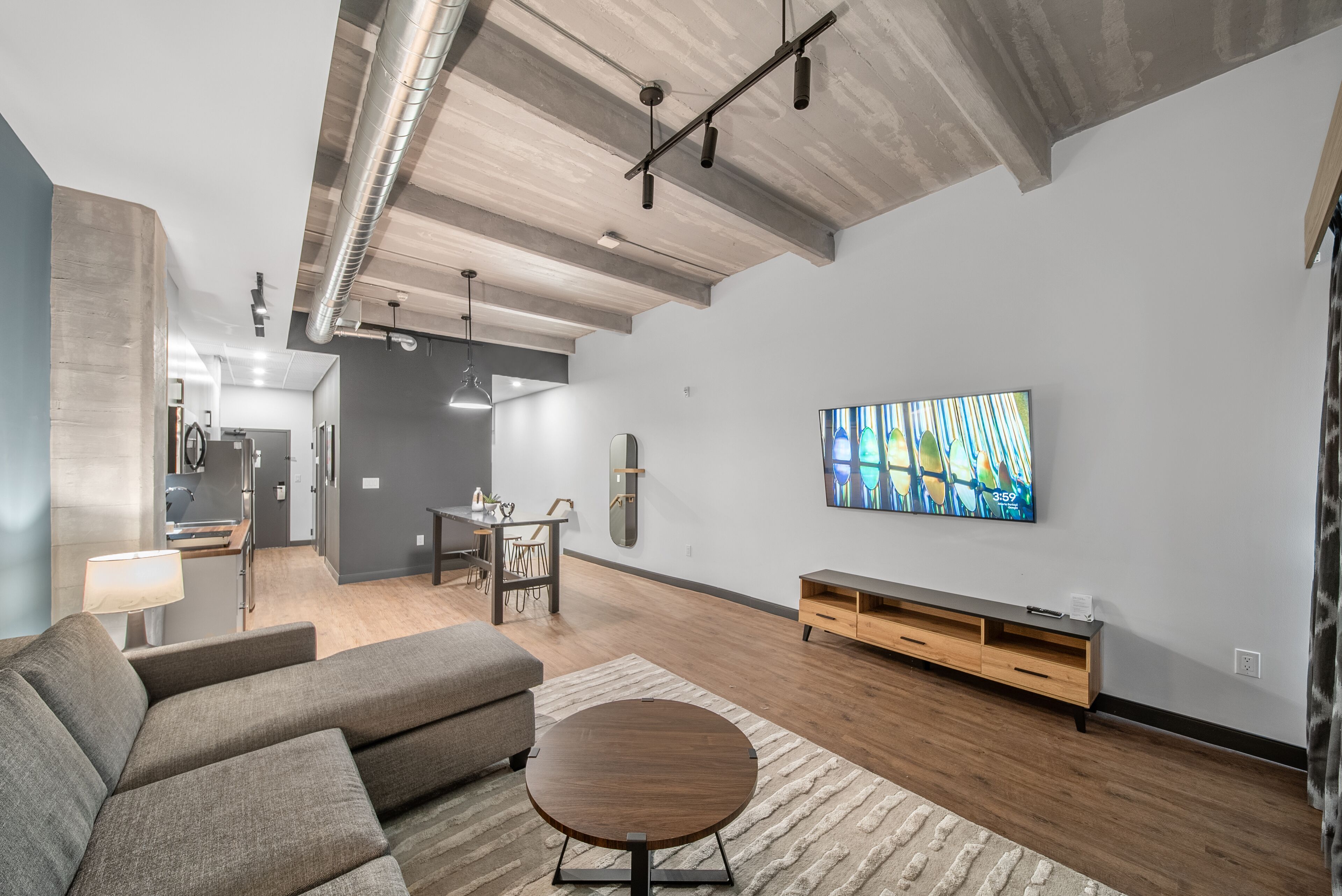 A modern living room with a sofa, coffee table, and a TV on the wall.
