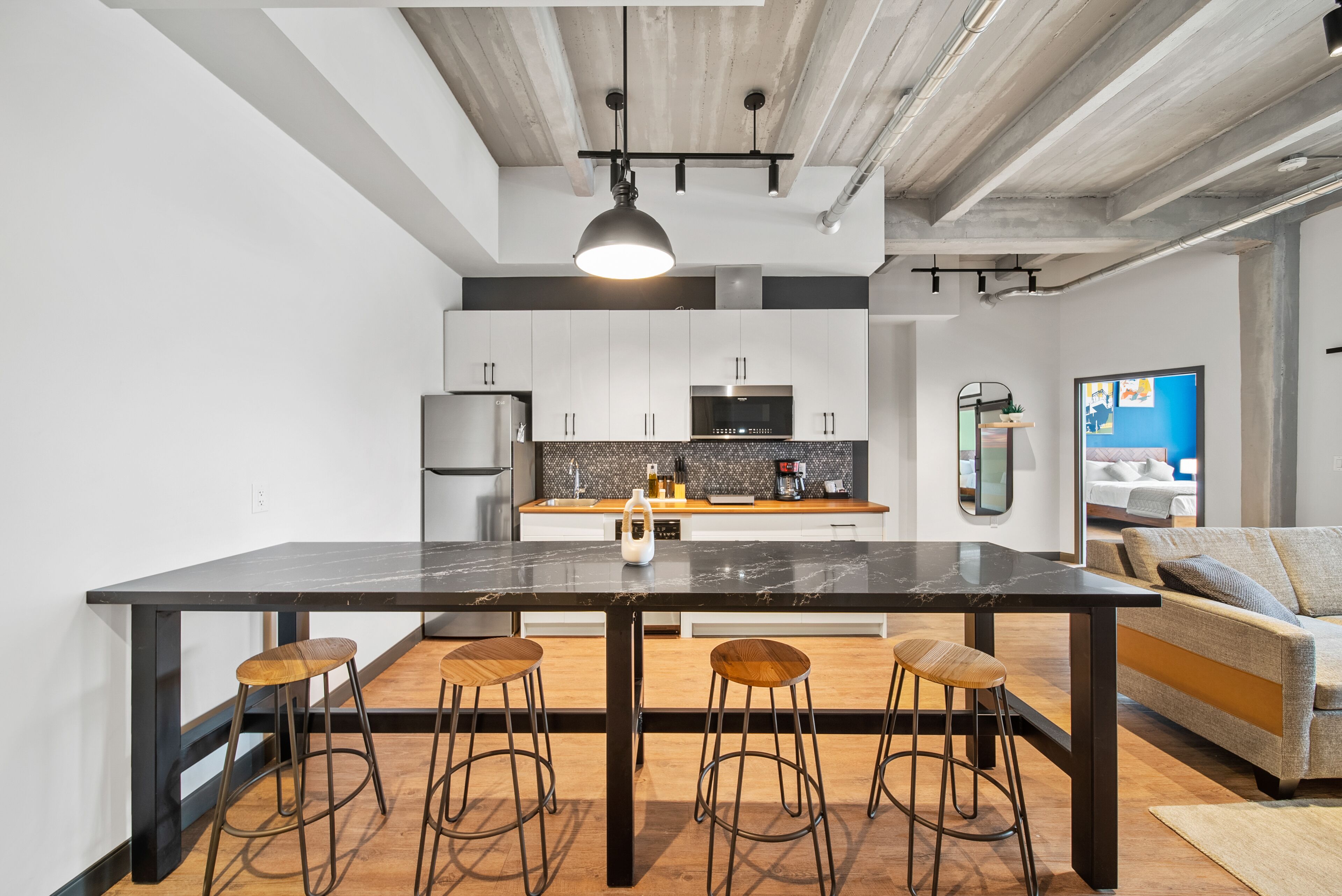 Una cocina moderna con una isla grande, taburetes de bar y un área de comedor con sofá.