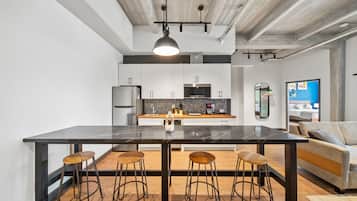 Una cocina moderna con una isla grande, taburetes de bar y un área de comedor con sofá.